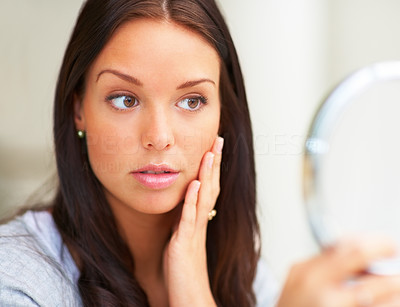Closeup portrait of a young lady looking into a hand mirror