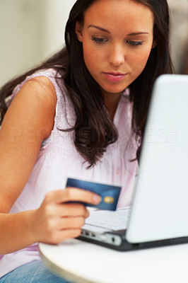 Portrait of young female holding a card and using laptop