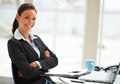 Businesswoman in black suit sitting in office and looking at camera