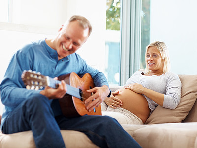 Man playing the guitar for his pregnant wife