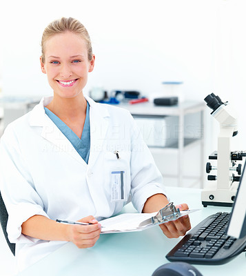 Smiling female researcher sitting at a laboratory and writing notes