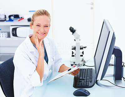 Smiling female researcher sitting in front of computer with notes