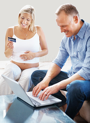 Mature pregnant couple shopping on internet with a credit card