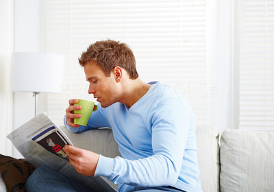 Contemporary man sitting reading newspaper at home