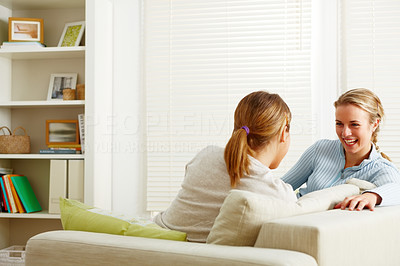 Two happy female friends sitting and chatting in the living room
