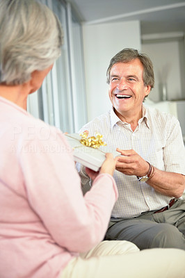 Happy retired man giving woman a present on birthday