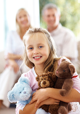 Sweet little girl with teddy bears while her parents sitting at back