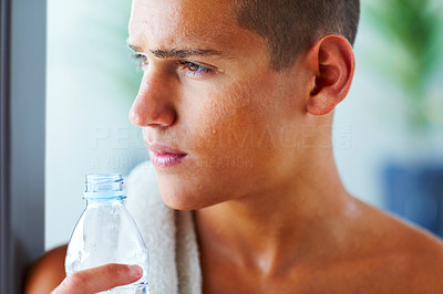 Young tired man with bottle of water looking away