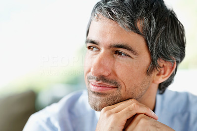 A thoughtful mature man with hands on chin looking away