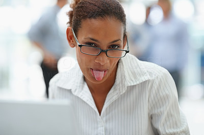 Young business woman sticking out her tongue while at work