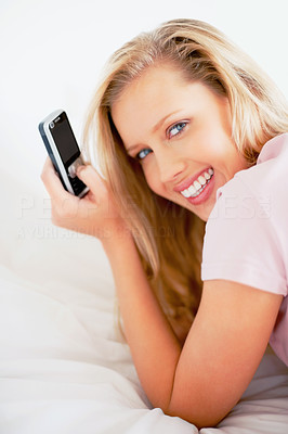 Happy cute female using her new cell phone while lying on bed