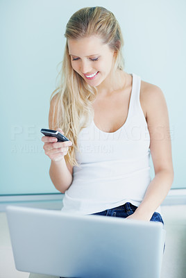 Happy woman with laptop and reading text message on cellphone