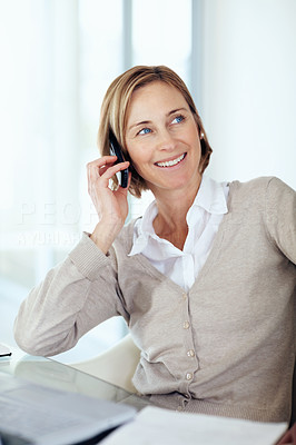 Happy middle aged businesswoman talking on mobile while at offic