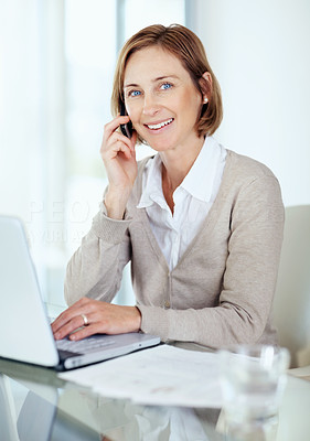 Happy mature businesswoman talking on mobile looking away