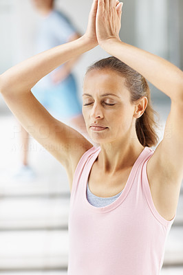 Mature woman practicing yoga with hands joined above head