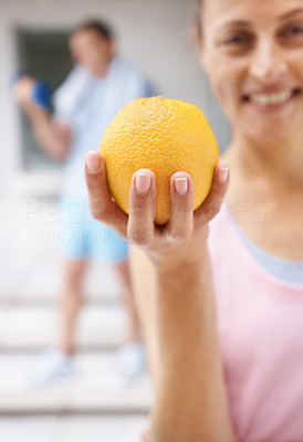 Woman holding a fresh orange while at the gym