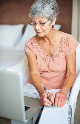 Senior woman writing with a laptop computer