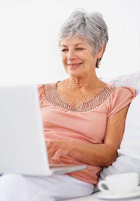 Smiling elderly woman using laptop to browse the internet