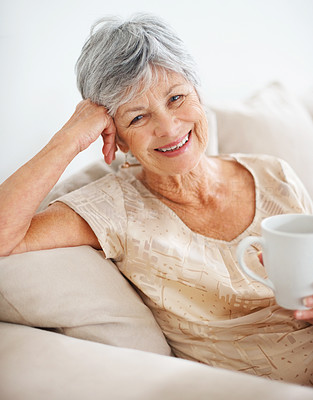 Closeup of a smiling old woman at home drinking coffee