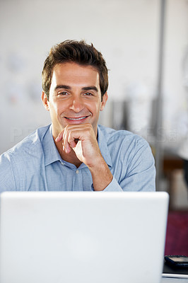 Happy businessman sitting in front of his laptop with a smile - portrait