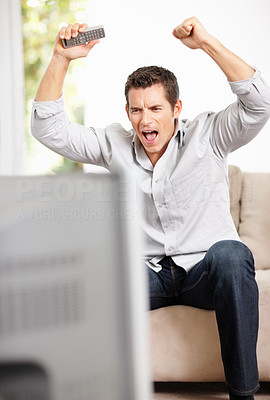 An excited middle aged man watching live match on television
