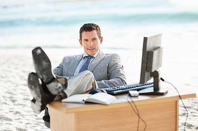 Relaxed middle aged business man at his desk on a beach