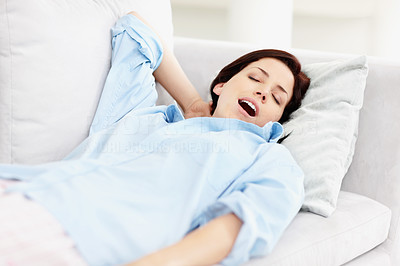 Sleepy young woman lying on sofa, yawning