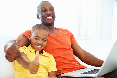 Father and son showing thumbs up while using laptop