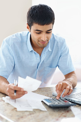 Young man checking home finances using a calculator