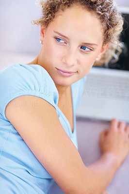 Closeup of a young girl looking behind while using laptop