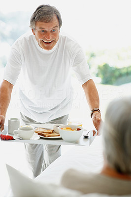 Retired man serving breakfast to the woman in bed