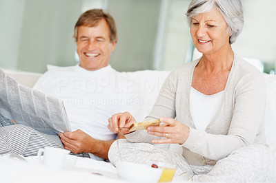 Smiling senior couple having a healthy breakfast in bed