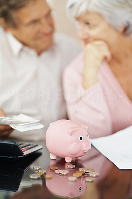 Unhappy couple with piggybank in front of them