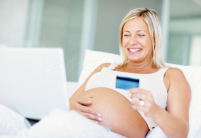 Happy pregnant woman using a credit card for online shopping