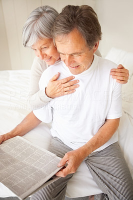 Happy retired senior couple smiling while reading the newspaper