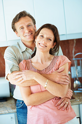 Mature man embracing a pretty woman in the kitchen