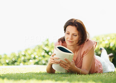 Pretty relaxed mature woman reading a book at the lawn