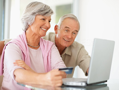 A senior couple shopping online using laptop