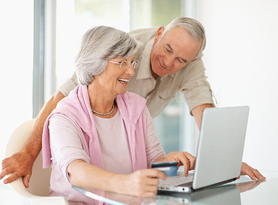 Senior couple using a laptop and a credit card to shop