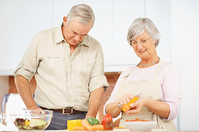 Elderly couple in the kitchen preparing salad