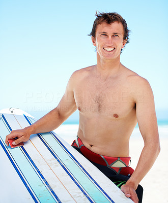 Portrait of a young surfer scraping the wax on his board with his credit card