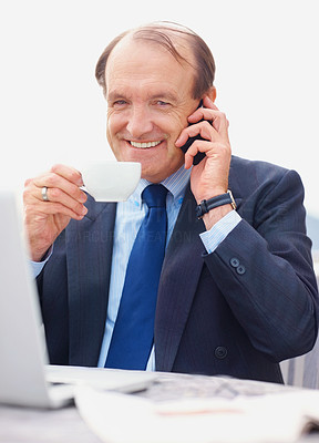 Senior business man with laptop on the phone while drinking