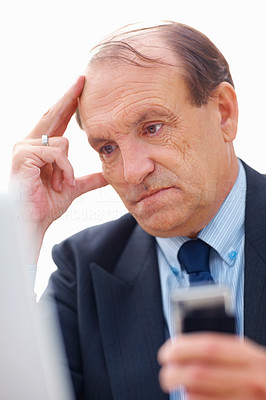 Closeup of a tensed senior business man holding a cell phone