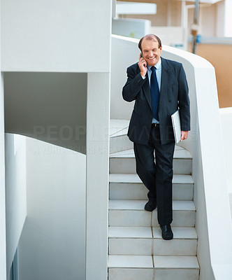 Senior business man using phone with a laptop on stairs
