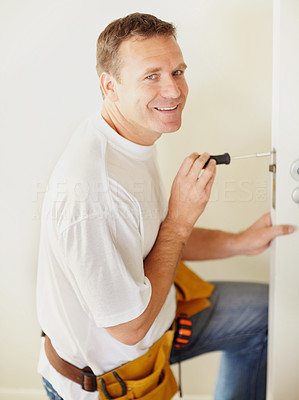 Smiling carpenter fixing a lock in the door