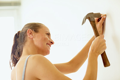 Woman hitting a nail into a wall using a hammer