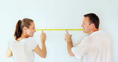 Smiling couple taking wall measurements with a measuring tape