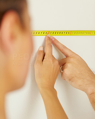 Closeup of people pointing at a measuring tape on the wall