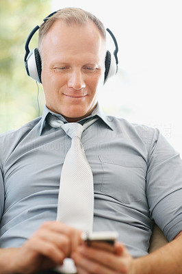 Successful business man enjoying music on an mp3 player