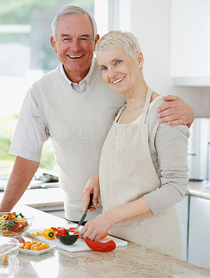 Smiling senior couple preparing food in the kitchen